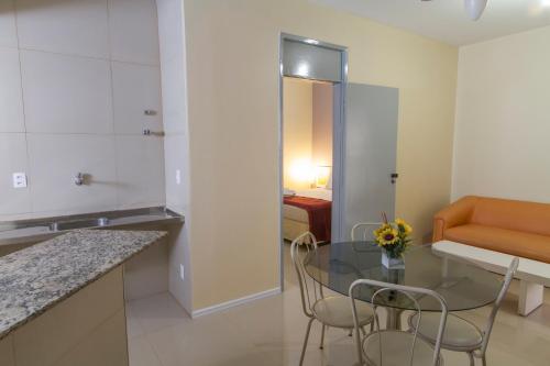 uma cozinha com uma mesa de vidro e cadeiras num quarto em San Phillip Flat Hotel em Fortaleza