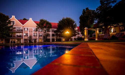a hotel with a swimming pool in front of a building at Southern Sun Bloemfontein in Bloemfontein