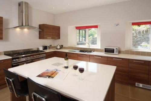 a kitchen with a white island with two glasses of wine at The Parsonage, Ambleside in Ambleside