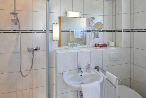 a white bathroom with a sink and a shower at Hotel Zum Grunewald in Dinslaken