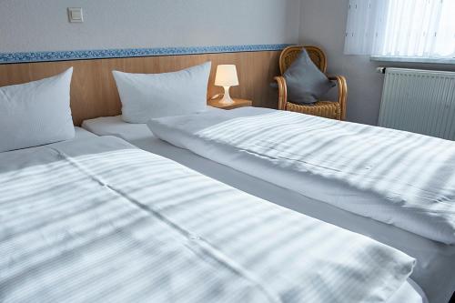 two beds in a bedroom with a lamp and a chair at Hotel Zum Grunewald in Dinslaken