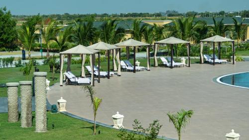 a resort with a pool and chairs and umbrellas at Hawthorn Suites by Wyndham Dwarka in Dwarka