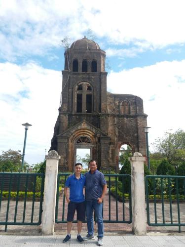 two men standing in front of an old building at Vagibi Hotel in Dong Hoi