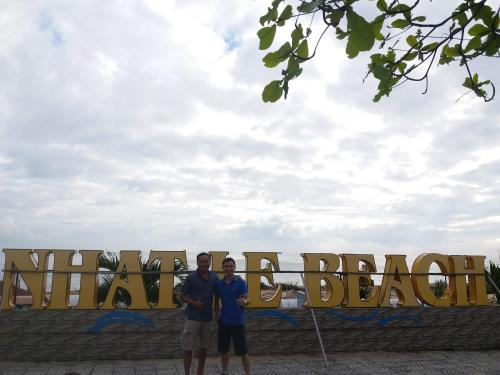 two men standing in front of a large sign at Vagibi Hotel in Dong Hoi