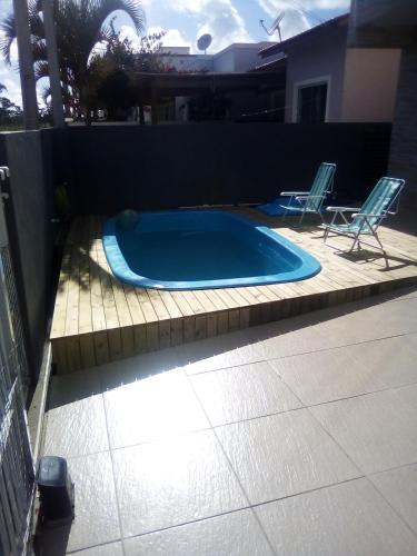 a small swimming pool with two chairs in a backyard at Casa no rio vermelho in Florianópolis