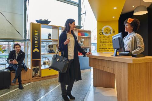 two women standing at a cash register in a store at Aparthotel Adagio Access Paris La Villette in Paris