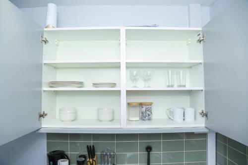a white cabinet with dishes and glasses on it at Wilmington Lodge Dartford London in Kent