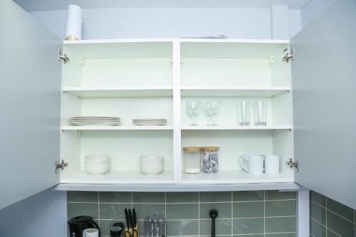 KentにあるWilmington Apartment Dartford Londonの白いキャビネット(皿、メガネ付)
