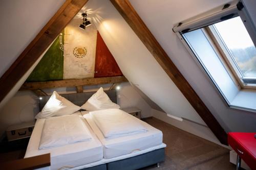 WarthausenにあるMotorworld Innのベッド2台と窓が備わる屋根裏部屋です。
