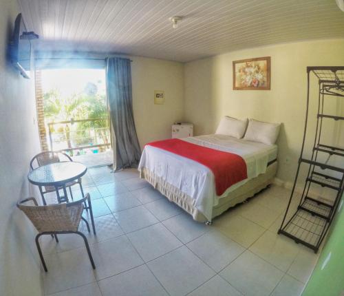 um quarto com uma cama, uma mesa e cadeiras em Pousada Paraíso das Palmeiras em Paripueira
