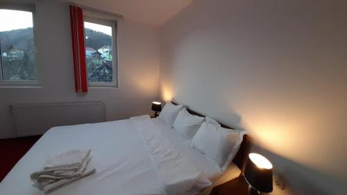 a bedroom with a bed with white sheets and a window at Pensiunea Lucy in Sinaia