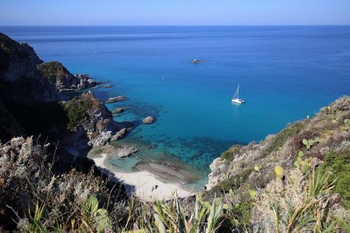 a boat in the water next to a beach at Hotel La Fattoria Sul Mare in Capo Vaticano