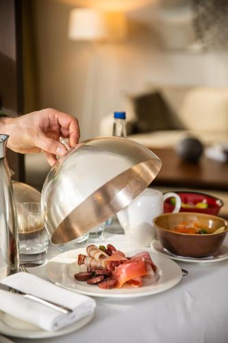 a person holding a pan over a plate of food at Hyatt Regency Belgrade in Belgrade