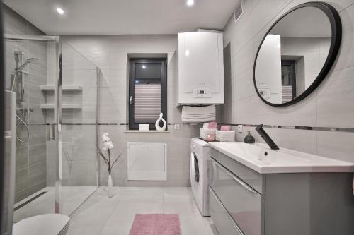 ein Bad mit einer Dusche, einem Waschbecken und einem Spiegel in der Unterkunft Domki Pod Lasem MM in Rabka-Zdrój