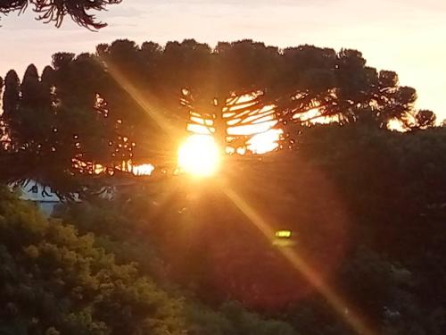 a sunset view of the sun shining through a tree at Eco-Residencial Martins in Apiaí