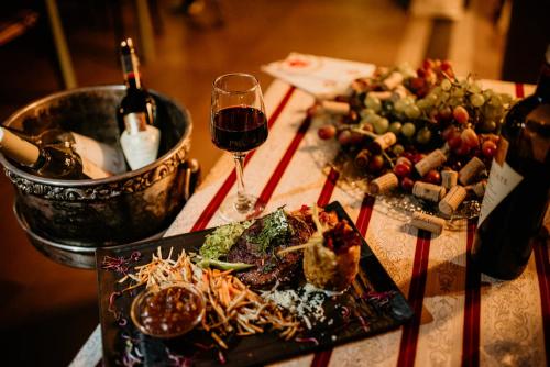 a table with a plate of food and a glass of wine at Hotel Coandi in Arad
