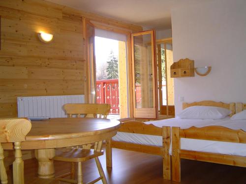 Schlafzimmer mit einem Bett, einem Tisch und einem Fenster in der Unterkunft Hotel Les Chalets in Brides-les-Bains