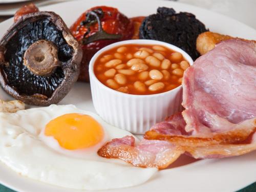 talerz jedzenia śniadaniowego z jajkami, fasolą bekonu i chlebem w obiekcie Poole Farm w mieście Launceston