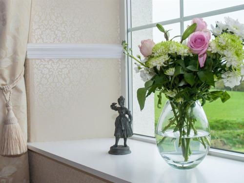a vase filled with flowers sitting on a window sill at Poole Farm in Launceston
