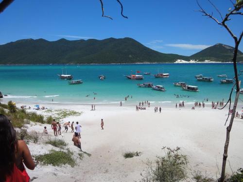 eine Gruppe von Menschen am Strand mit Booten im Wasser in der Unterkunft Apartamento Jamesson Cabo Frio in Cabo Frio