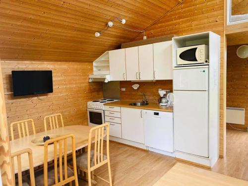 a kitchen with a table and a white refrigerator at Hummingen Camping hus 1 in Dannemare