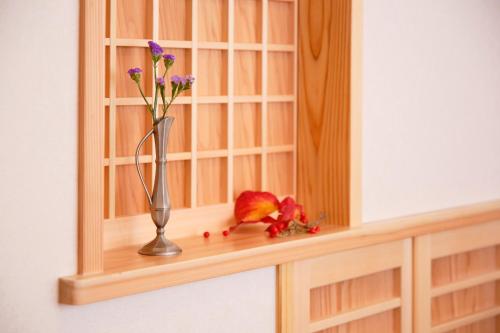 a vase with flowers on a shelf in a mirror at 肖舎 Shoya in Nara