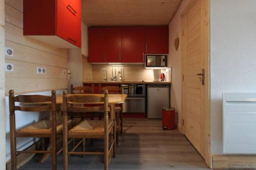 une cuisine avec des armoires rouges et une table et des chaises dans l'établissement Bel appartement 25m2 exposé plein sud, à Val Thorens