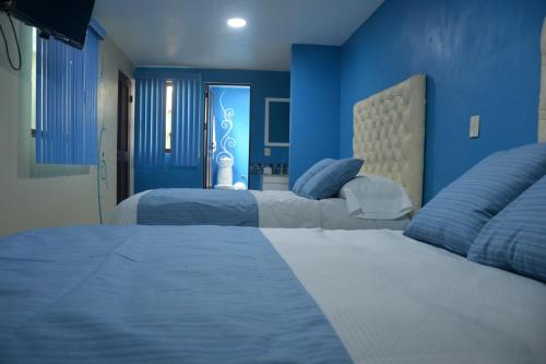 a bedroom with two beds with blue walls at Andrea´s Hotel Boutique in Zacatlán