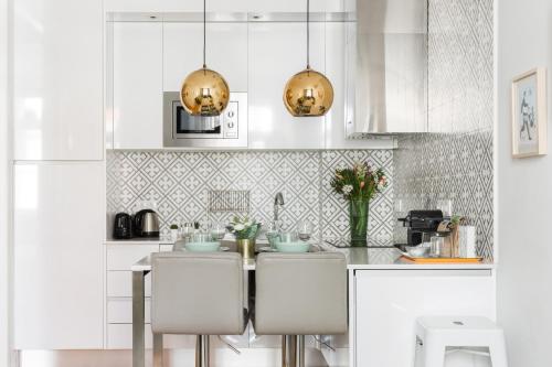 a kitchen with white cabinets and gold pendant lights at Augusta Street 213 - 3 Esq in Lisbon