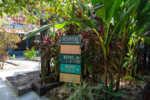a directional sign in a garden with plants and flowers at Point Break Santa Teresa in Santa Teresa Beach