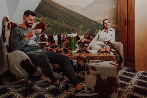 a man and a woman sitting at a table in a room at Serce Tatr Residence Zakopane - blisko Krupówek in Zakopane