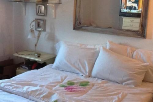 1 cama con sábanas y almohadas blancas y espejo en Apartamento charmoso com piscina, en Gramado
