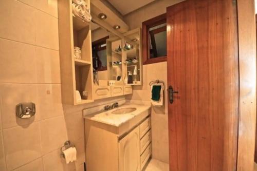 Un baño pequeño con lavabo y espejo. en Apartamento charmoso com piscina, en Gramado