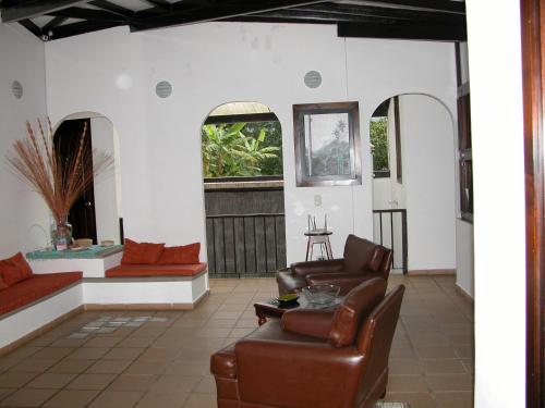a living room with leather furniture and two windows at Casa de la Ciencia in Salento