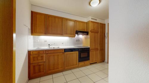 a kitchen with wooden cabinets and a sink at Mountain Escape Apartment for 5 in Leukerbad in Leukerbad