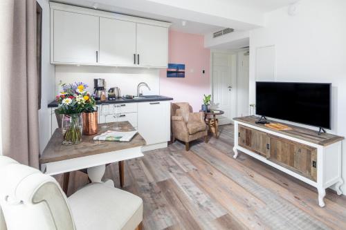 eine Küche und ein Wohnzimmer mit einem Flachbild-TV in der Unterkunft Heimathafen Juist in Juist