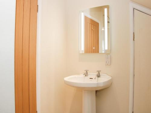 y baño con lavabo blanco y espejo. en Brynlikky Cottage, en Bucknell