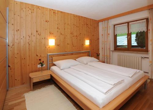 a bedroom with a large white bed and a window at Pension Matt in Schoppernau