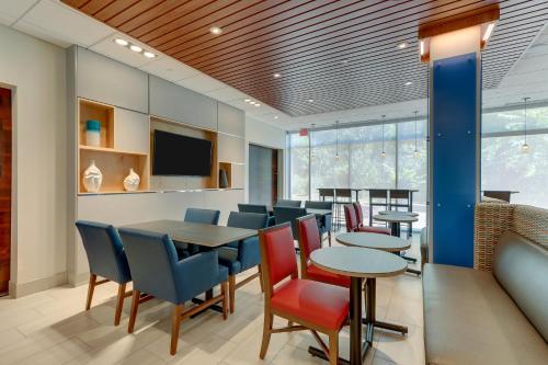 a dining room with tables and chairs and a tv at Holiday Inn Express & Suites - Roanoke – Civic Center in Roanoke