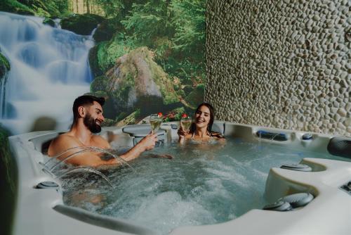 a man and woman in a bathtub in a waterfall at Serce Tatr Residence Zakopane - blisko Krupówek in Zakopane