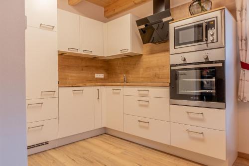a kitchen with white cabinets and a microwave at BergAufe Chalets Mallnitz in Mallnitz