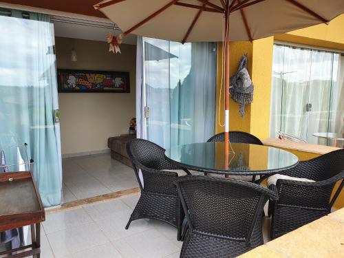 een eettafel met stoelen en een parasol bij Winterville Resort Flat 910 Gravatá-Pe in Gravatá