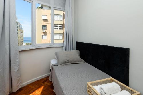 ein Schlafzimmer mit einem Bett und einem großen Fenster in der Unterkunft 2 quartos em Copacabana c/ Vista Mar | PJ 135/808 in Rio de Janeiro