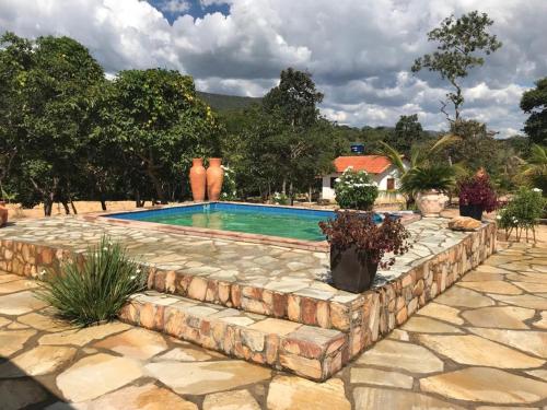 a swimming pool with a stone wall around it at Rancho do Paollo in Pirenópolis