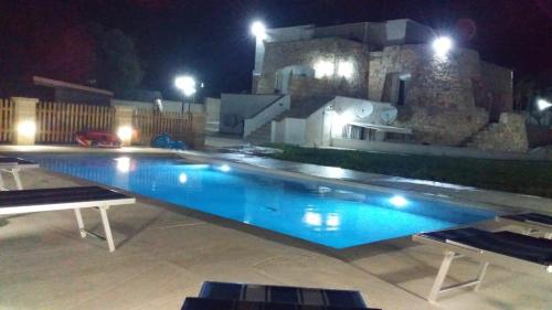 a swimming pool at night with a building in the background at La stanza del paradiso in Torre Pali 