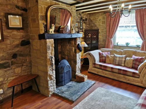 a living room with a stone fireplace and a couch at Pathways Cottage in Higham