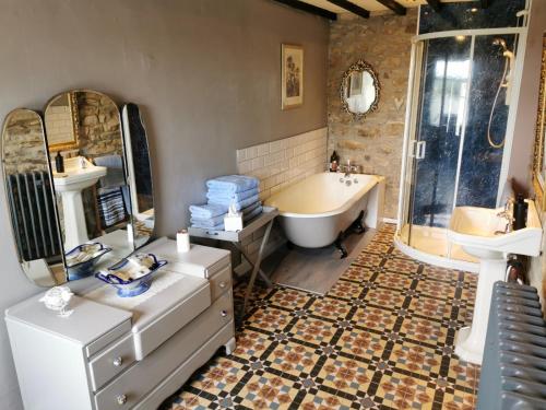 y baño con bañera, lavamanos y bañera. en Pathways Cottage en Higham