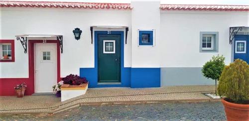 a white house with a green door and blue trim at Olívale - Turismo Rural in Campo Maior