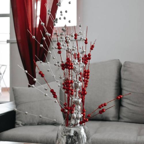 a glass vase with red berries and christmas decorations at Gold apartman in Sombor