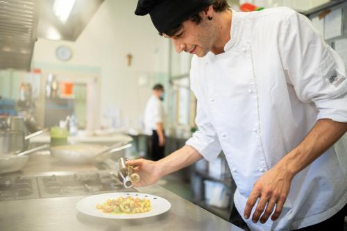 a chef preparing a plate of food in a kitchen at Hotel Ariston Molino Buja in Abano Terme